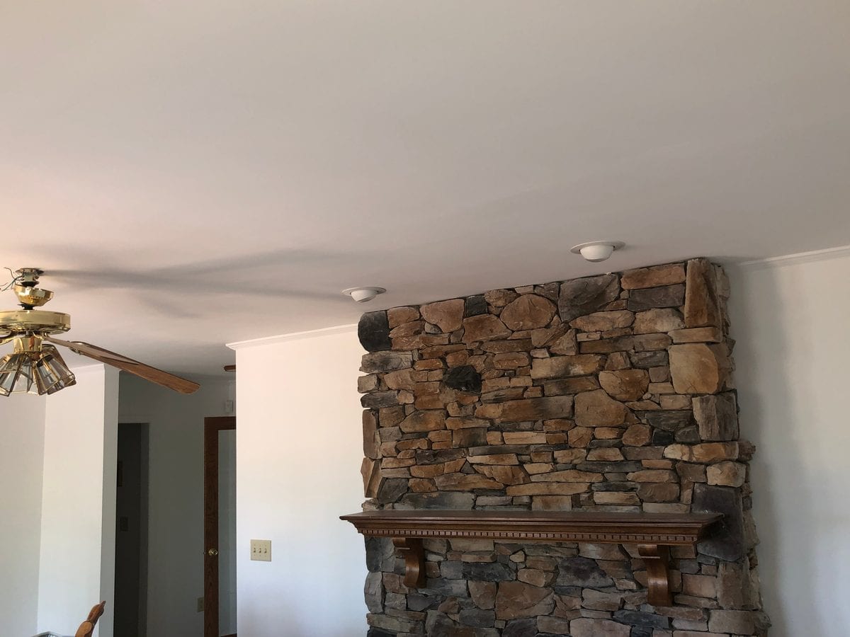 Living room with stone fireplace after walls and ceiling were repainted